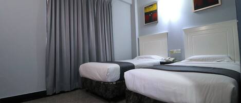 Una habitación de hotel con dos camas, cortinas grises y obras de arte en las paredes.