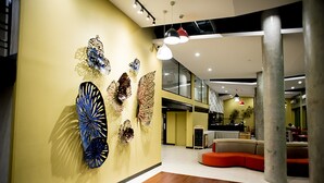 Ein modernes Interieur mit einer gelben Wand, Wandkunst, Holzboden und einer Sitzecke mit einem roten Kissen.