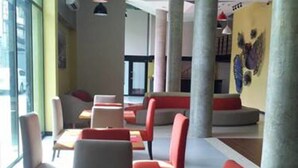 Ein modernes Restaurant mit roten und weißen Stühlen, Tischen mit Besteck und Pendelleuchten.