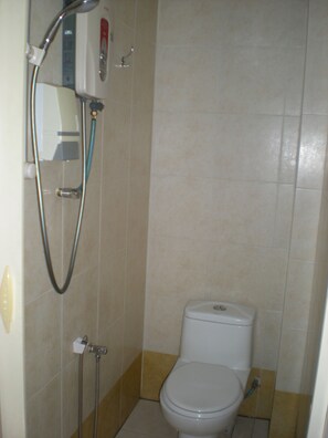 Un baño pequeño con inodoro, ducha y secamanos.