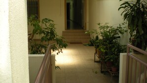 A narrow corridor with potted plants on both sides, leading to a door at the end. - Friendship Motel (George Town)