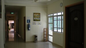A hotel corridor with a ceiling fan, a fire extinguisher, a trash bin, and a door with a number. - Friendship Motel (George Town)