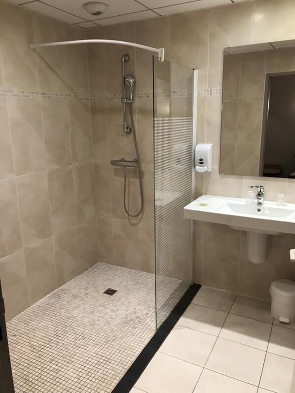 Un baño moderno con ducha de vidrio, lavamanos blanco y espejo sobre el lavamanos.