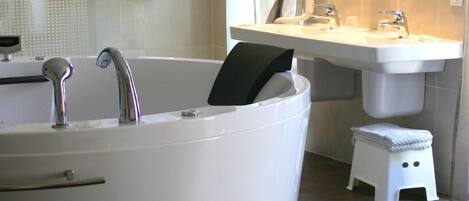 Un baño con bañera, lavamanos y un taburete pequeño.