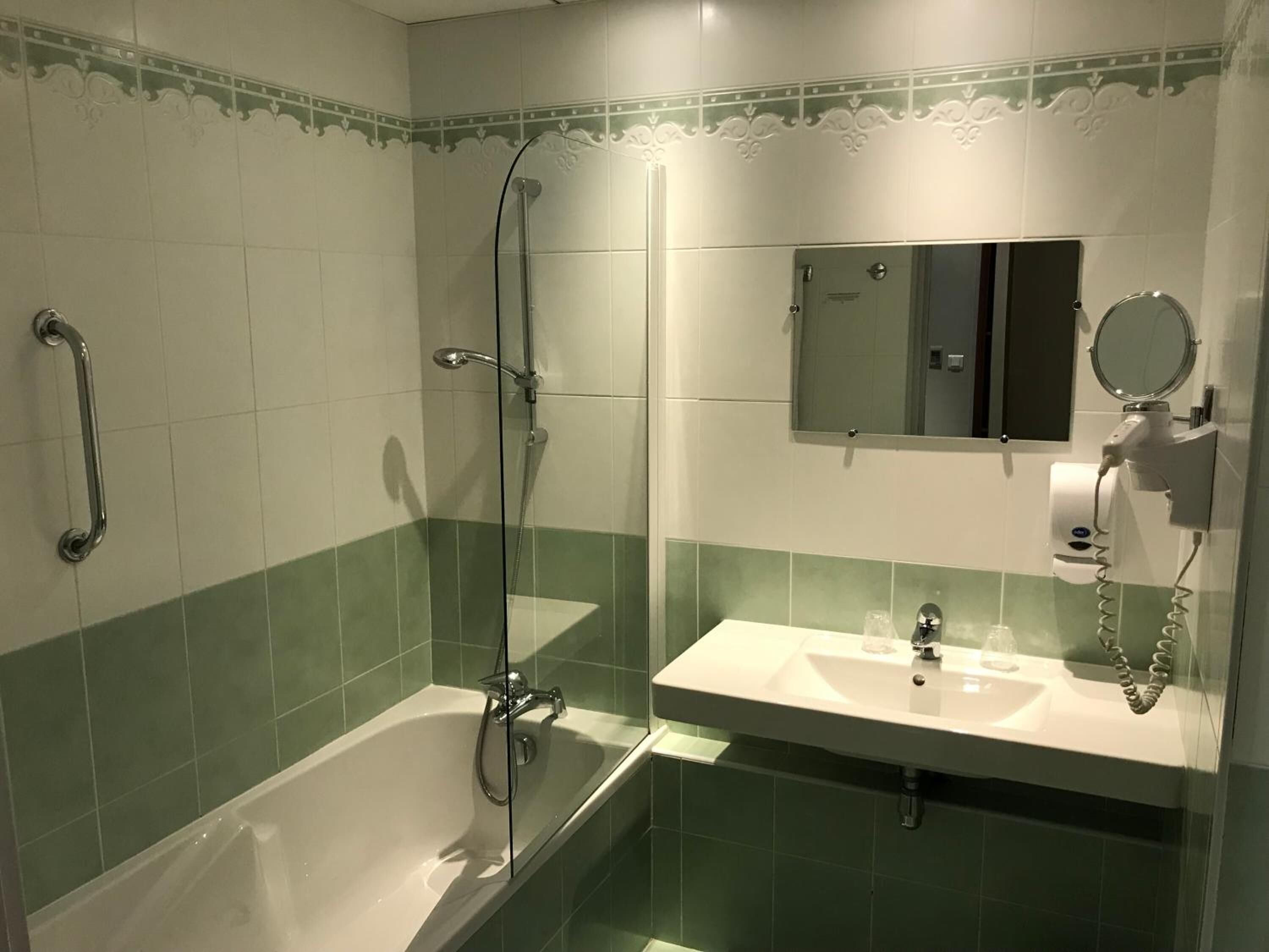 Een badkamer met een bad, een douche, een wastafel en een spiegel.