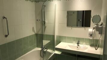 Een badkamer met een bad, een douche, een wastafel en een spiegel.