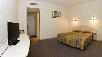 Een hotelkamer met een bed, een bureau met een computer en een televisie.