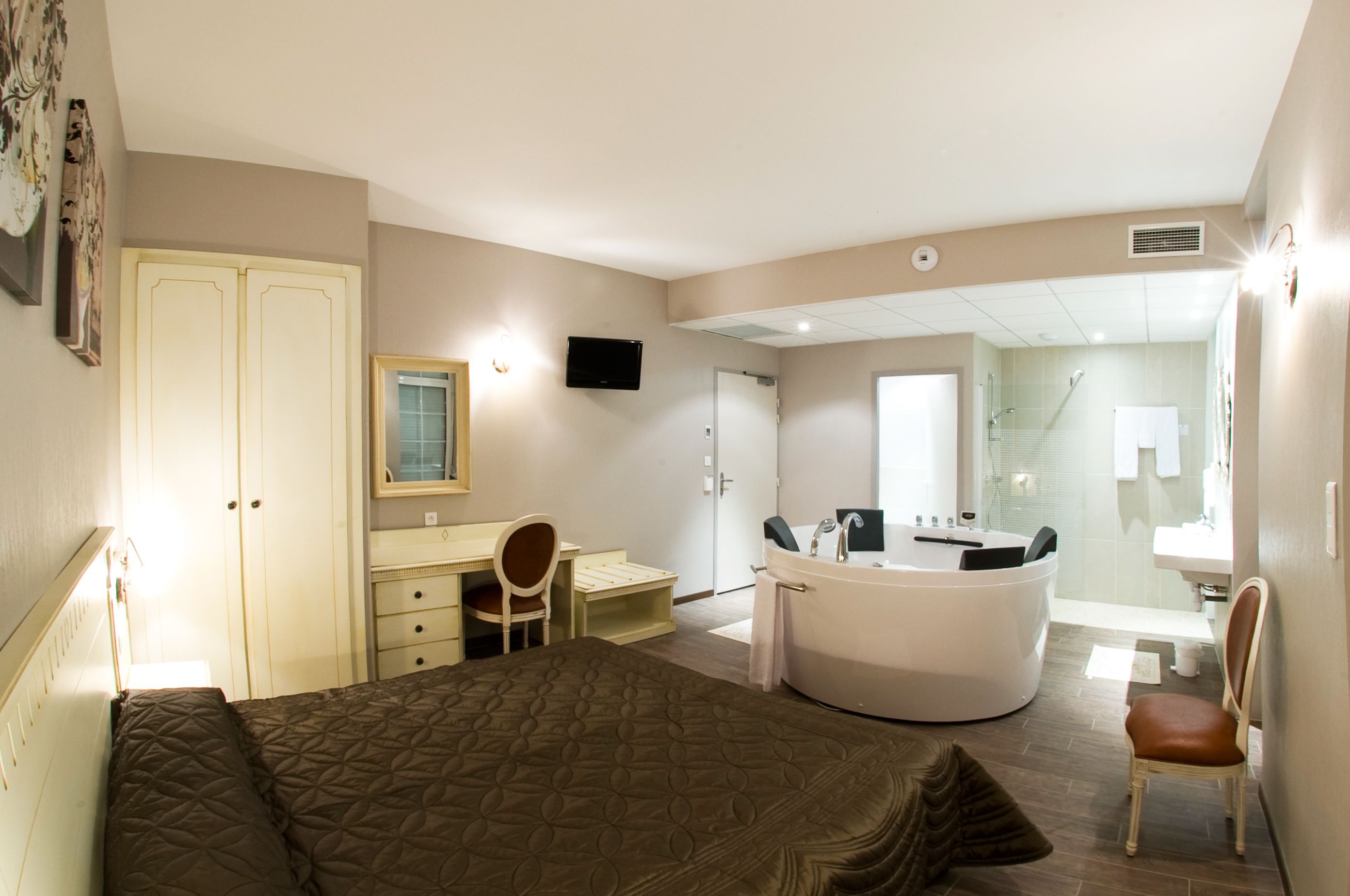 A hotel room with a bed, a desk, a chair, a bathroom with a bathtub, and a shower.