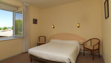A bedroom with a bed, two chairs, a window, and two wall-mounted lights.
