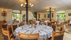 Un comedor amplio con mesas redondas dispuestas para varios comensales, con manteles blancos y sillas de madera.