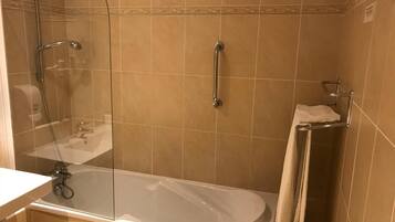 A bathroom with a glass-enclosed shower, a white bathtub, and a towel rack.