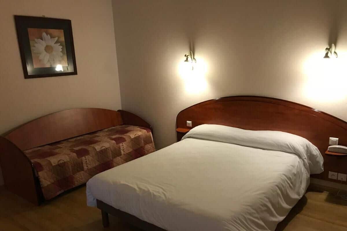 Ein Hotelzimmer mit einem Bett, einer Couch und zwei Wandleuchten.