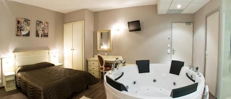 Un dormitorio con una bañera grande, una cama, un escritorio y una silla.