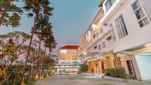 A multi-story hotel with a red roof, a covered outdoor area with plants, and a paved courtyard. - The Salak Hotel (Denpasar)