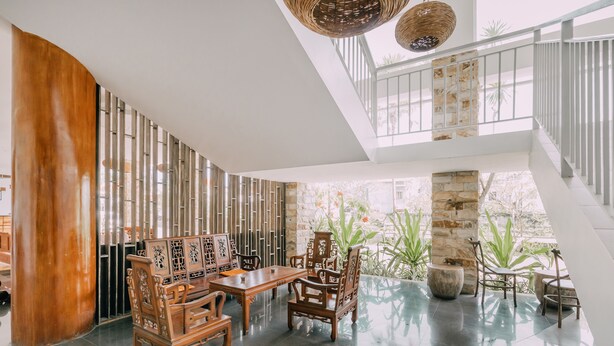 A spacious indoor area with a high ceiling, a wooden dining set, and a stone pillar. - The Salak Hotel (Denpasar)