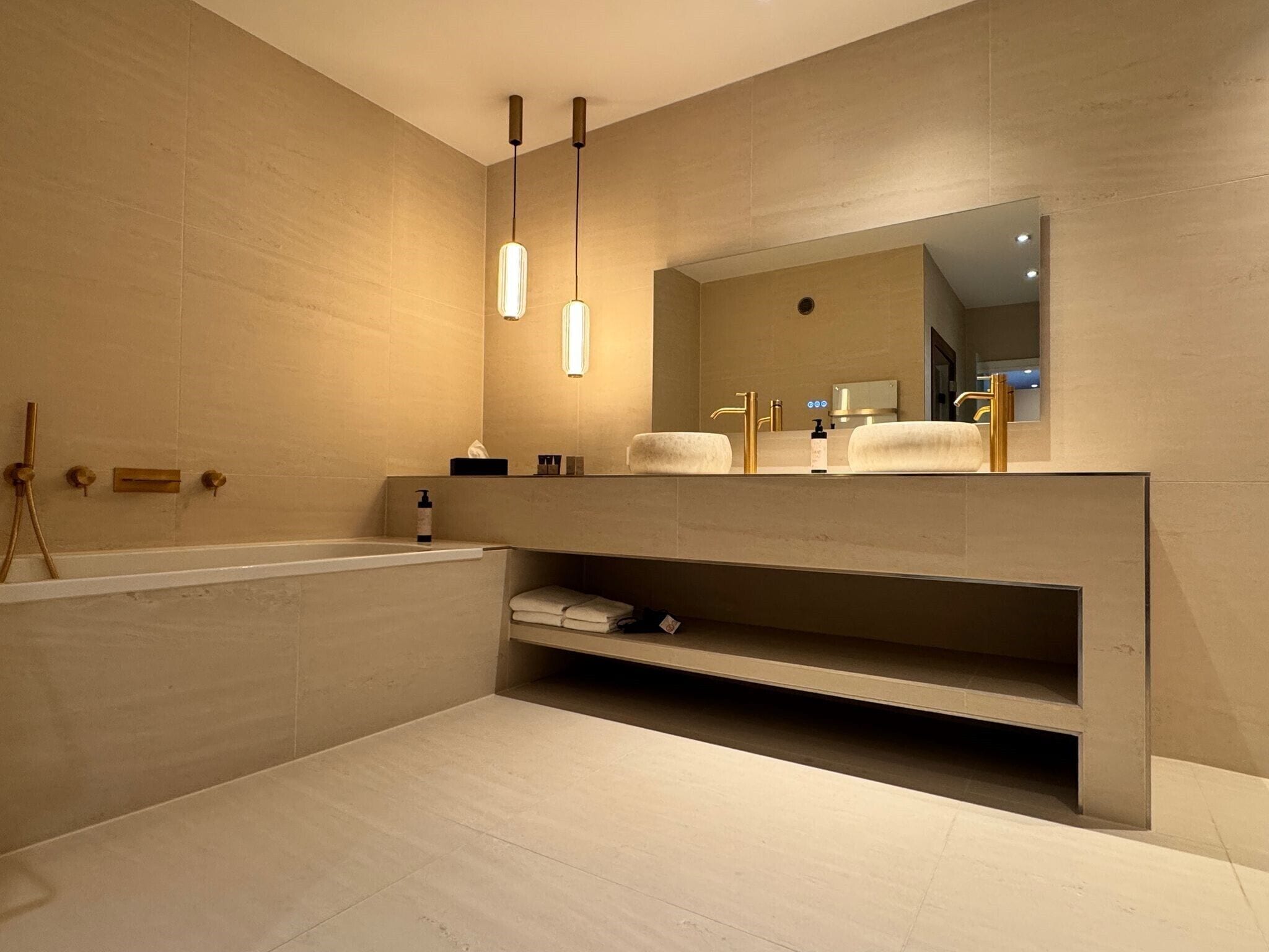 Ein modernes Badezimmer mit Badewanne, Waschtisch mit Spiegel und Pendelleuchten.