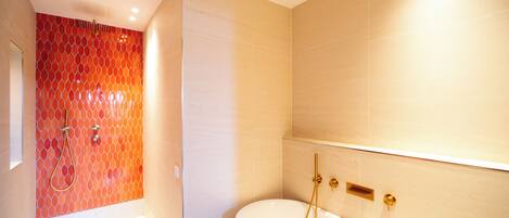 Un baño moderno con ducha, bañera y pared de azulejos.