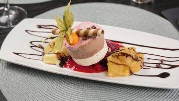 Une assiette à dessert avec une boule de glace, une compote de fruits rouges et un filet de chocolat.
