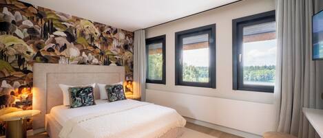 Un dormitorio con una cama grande, un mural en la pared y tres ventanas.