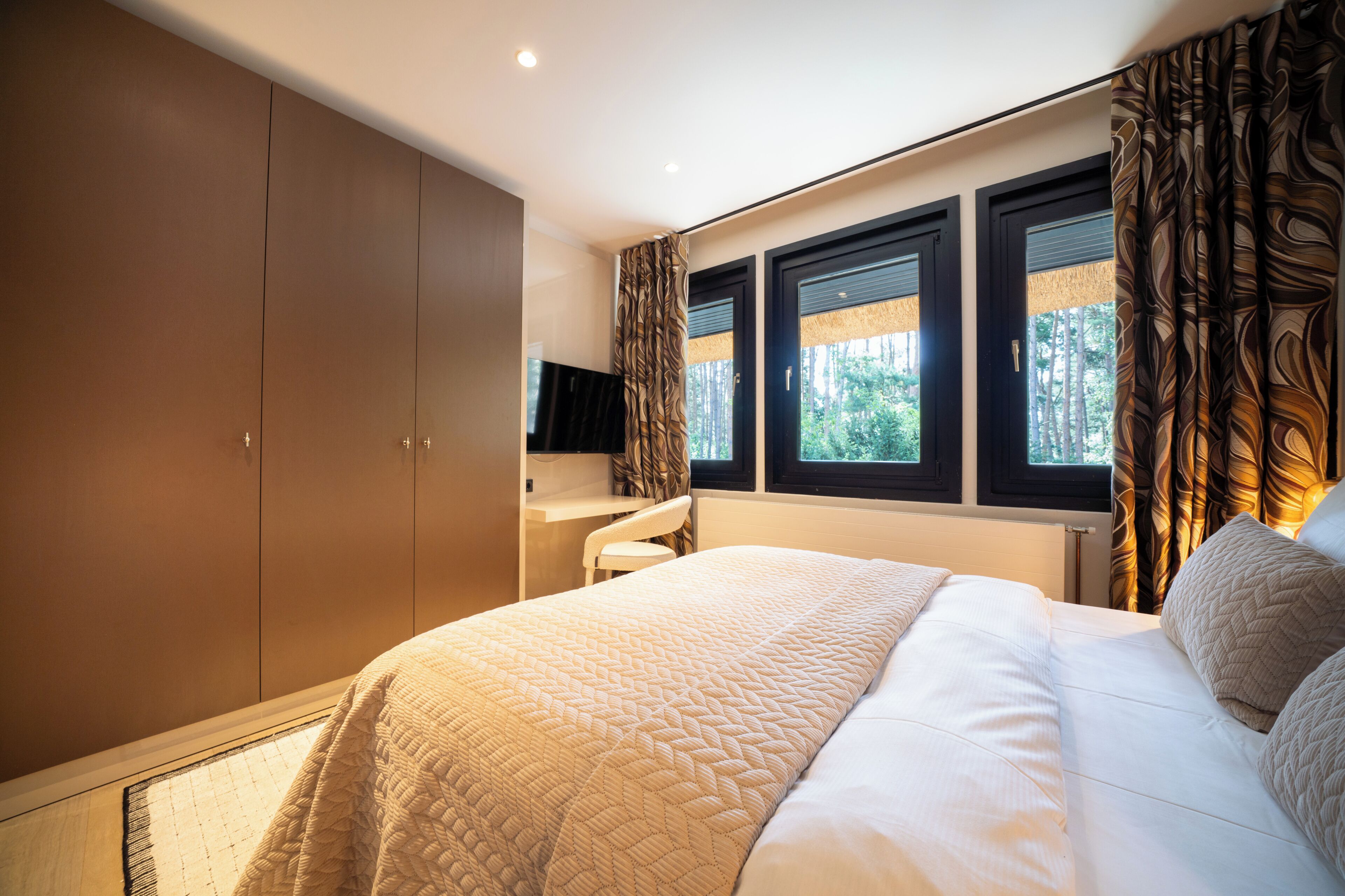 A bedroom with a bed, a desk, and a wardrobe.
