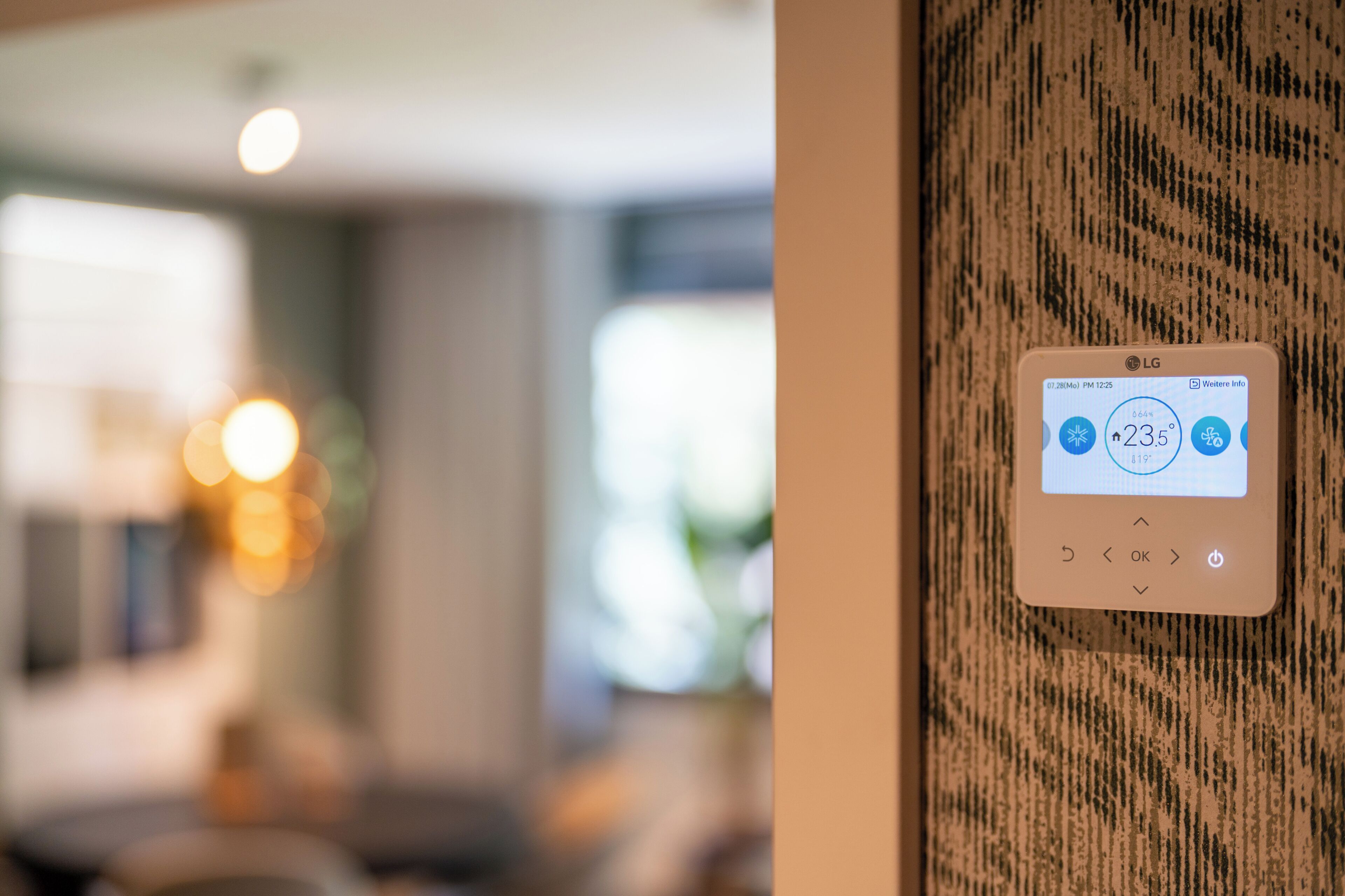 A thermostat on a textured wall displaying a temperature of 23.5°C.