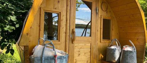 Une cabane en bois avec une porte, deux fenêtres et un banc sur lequel sont posés des sacs.