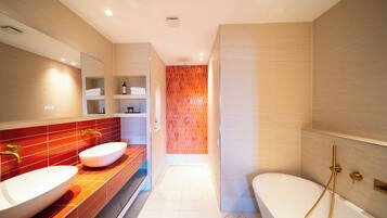 A modern bathroom with two sinks, a bathtub, and a shower.