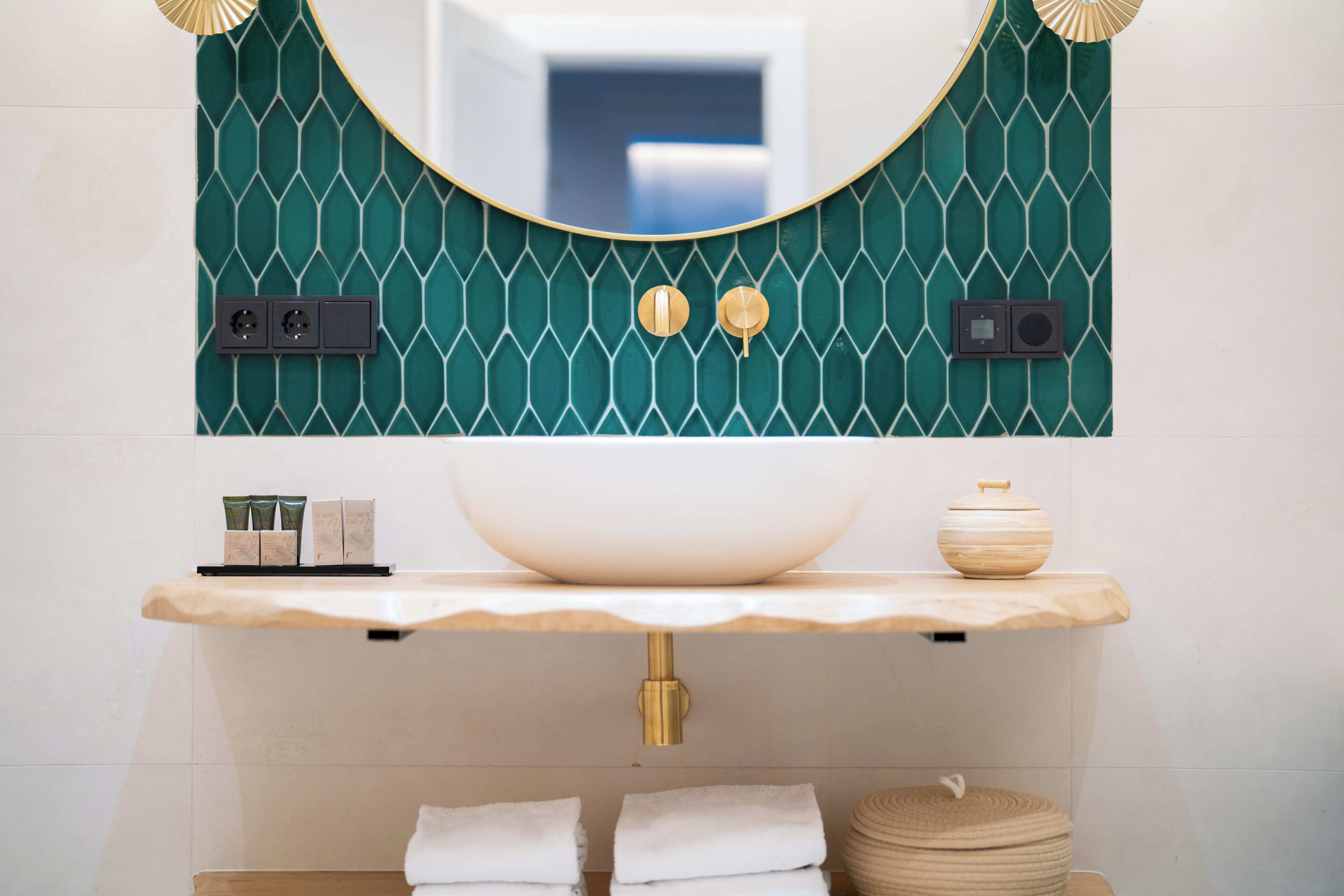 A bathroom with a large mirror, a white sink, and a green patterned wall.