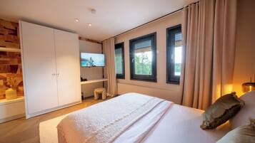 Een moderne slaapkamer met een groot bed, een televisie, een garderobe en een raam met gordijnen.
