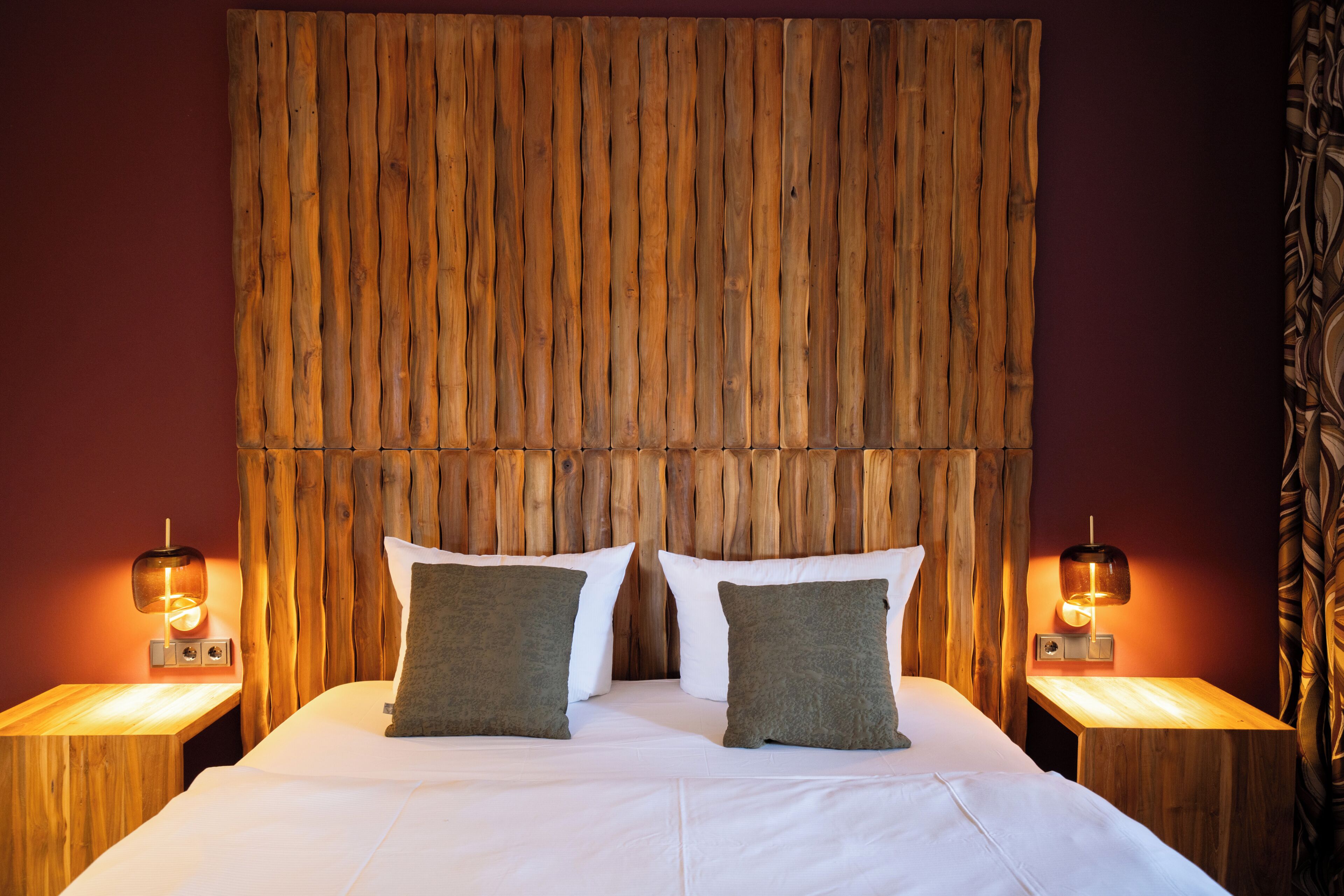 A bed with a wooden headboard, two bedside tables with lamps, and two pillows.