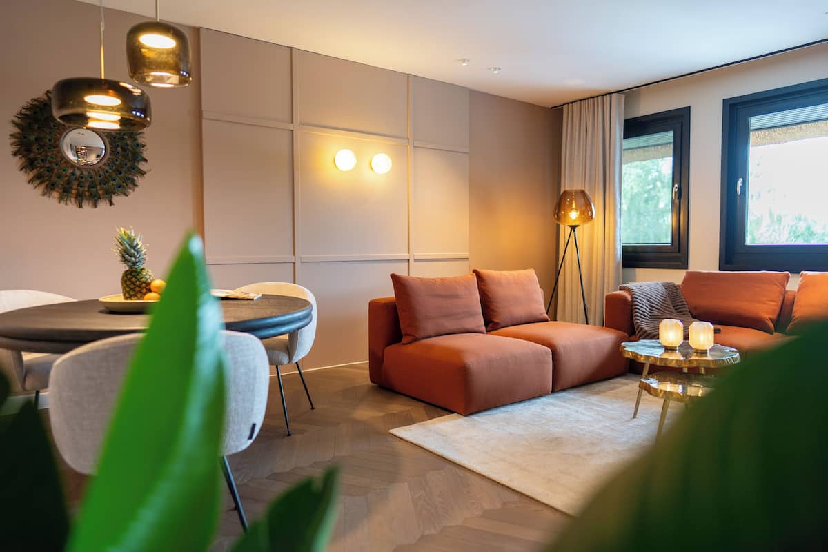 Uma sala de estar moderna com um sofá, uma mesa de jantar e um abajur.