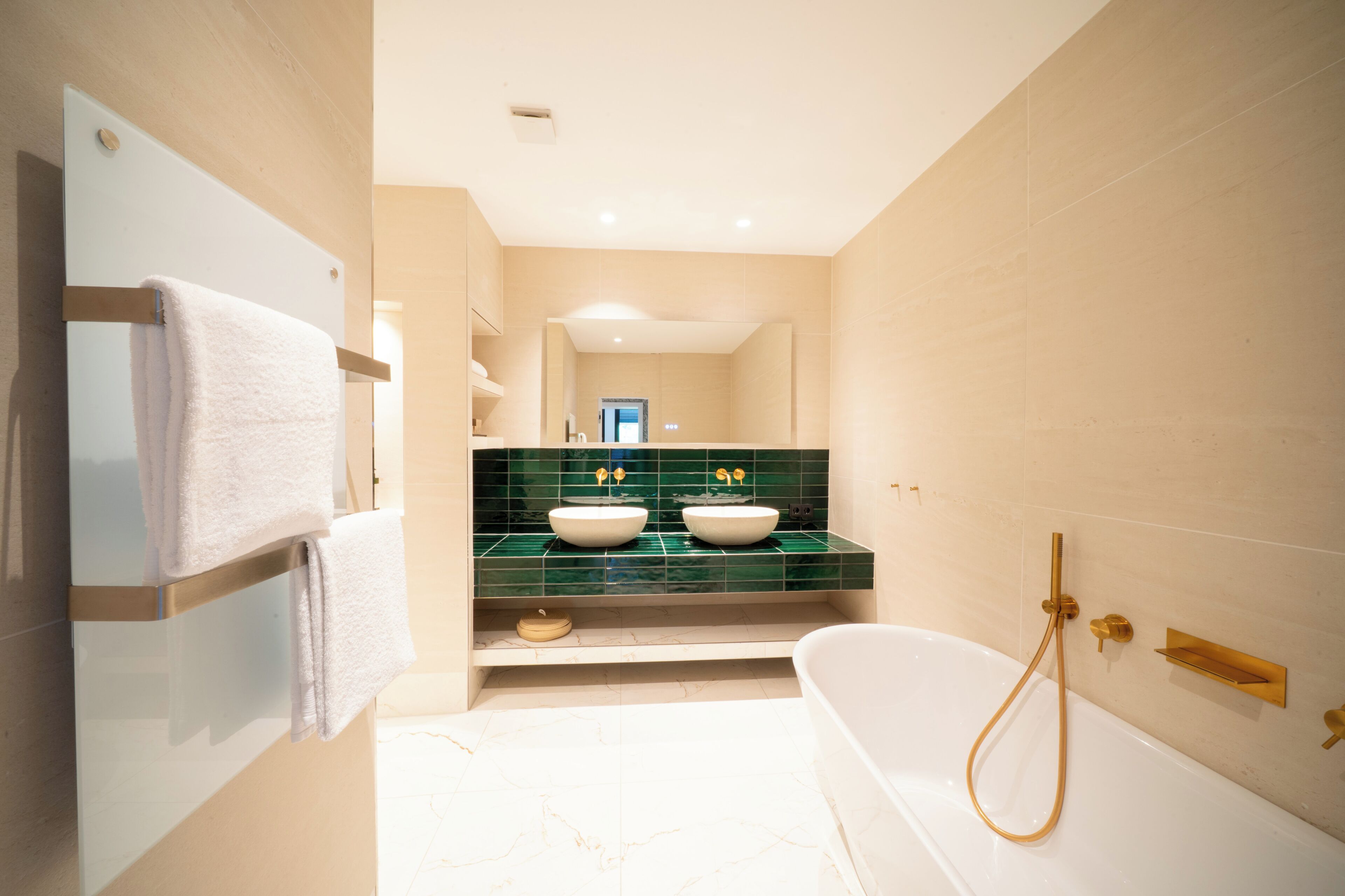 A modern bathroom with a bathtub, two sinks, and a towel rack.