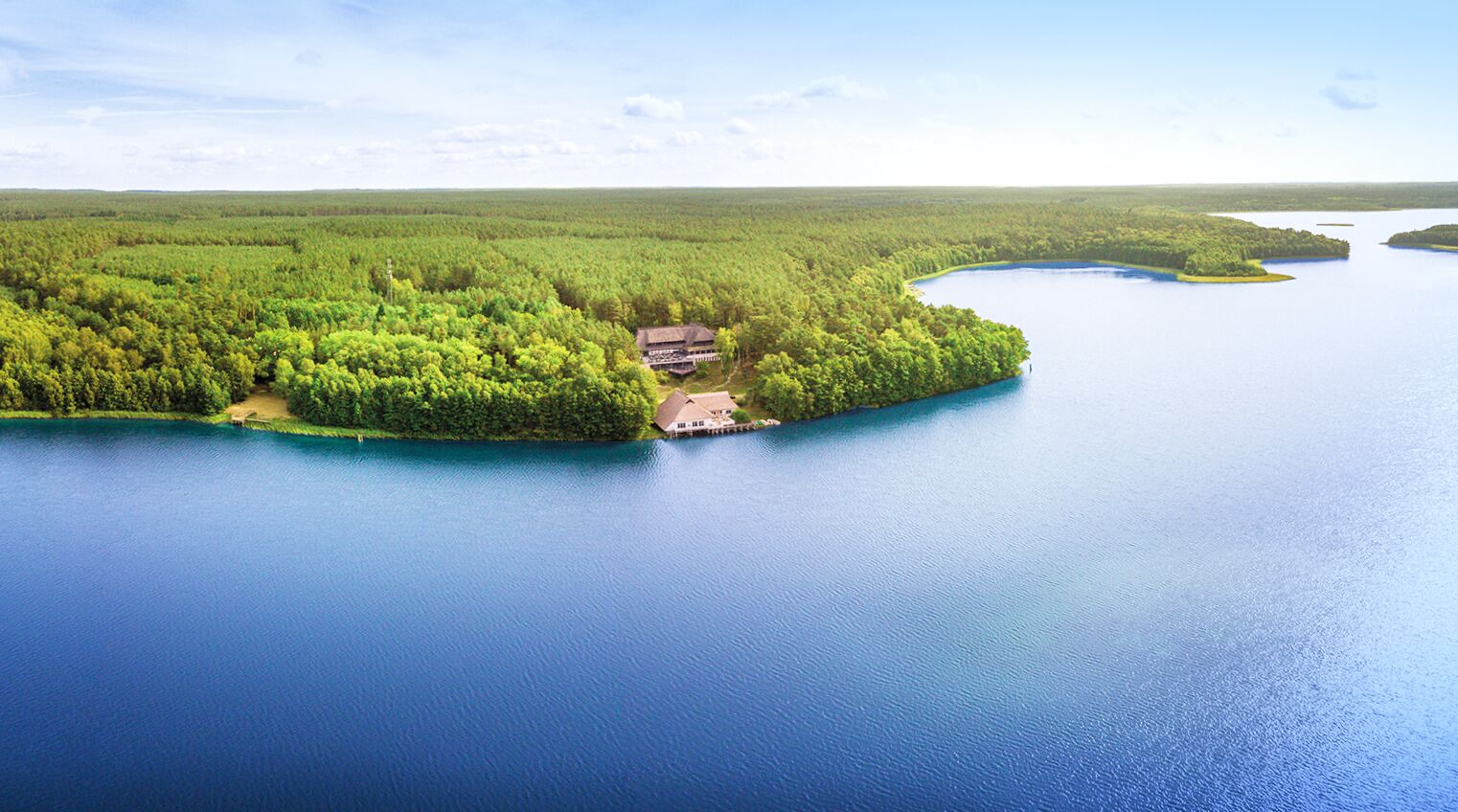 A large body of water with a forested island and a building with a dock.