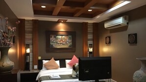 A hotel room with a bed, a flat-screen TV, a vase with flowers, and a painting on the wall. - Budsaba Resort & Spa (Bang Lamung)