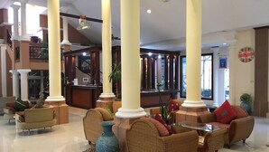 A spacious lobby with high ceilings, large columns, and a central seating area with wicker furniture. - Budsaba Resort & Spa (Bang Lamung)