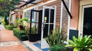 A building entrance with a glass door, a brick pathway, and various potted plants. - Budsaba Resort & Spa (Bang Lamung)
