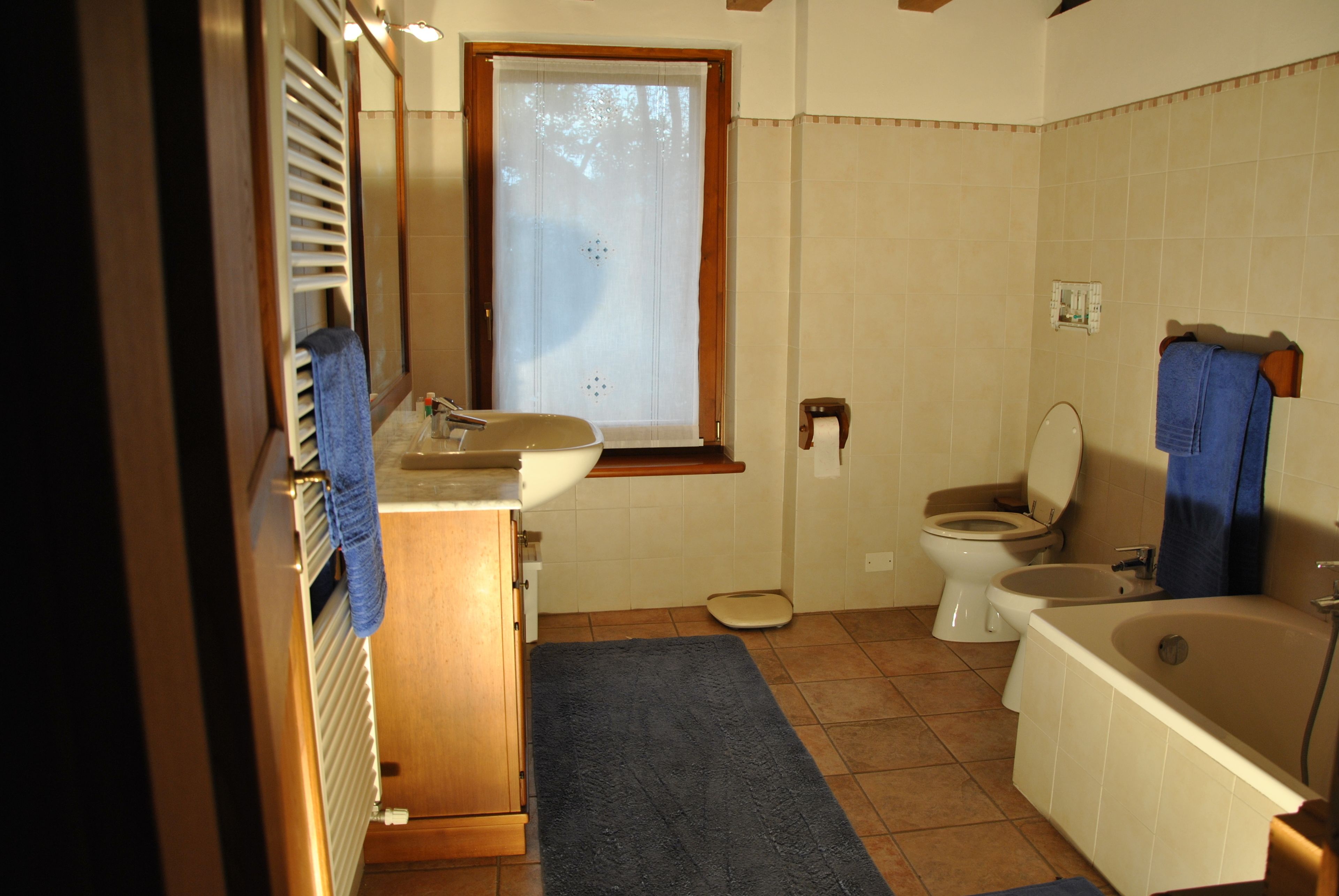 Une salle de bain équipée d’un lavabo, de toilettes, d’une baignoire et d’une fenêtre avec des stores.