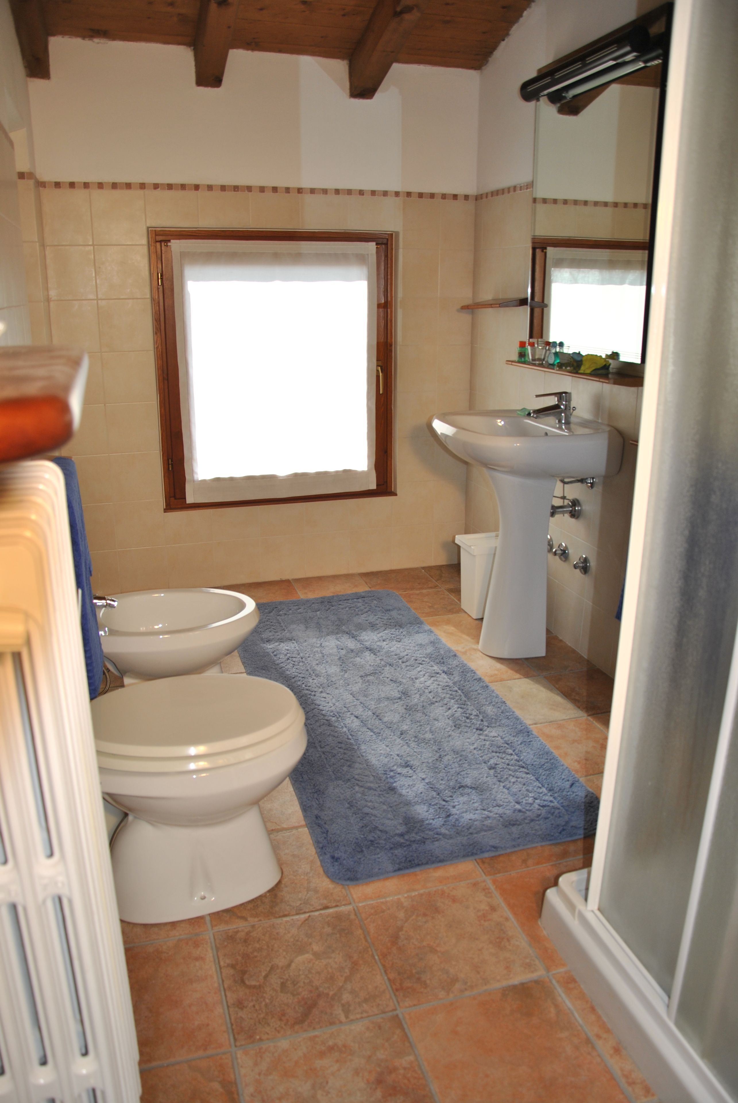 Un baño con inodoro, bidé, lavamanos y ventana.