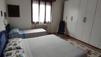 A bedroom with two beds, a chair, a wardrobe, and a radiator.