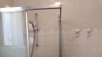 Un baño con cabina de ducha de vidrio, tocador con cajones y suelo de baldosas.