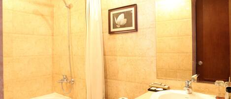 A bathroom with a bathtub, shower, toilet, sink, and a framed picture on the wall.