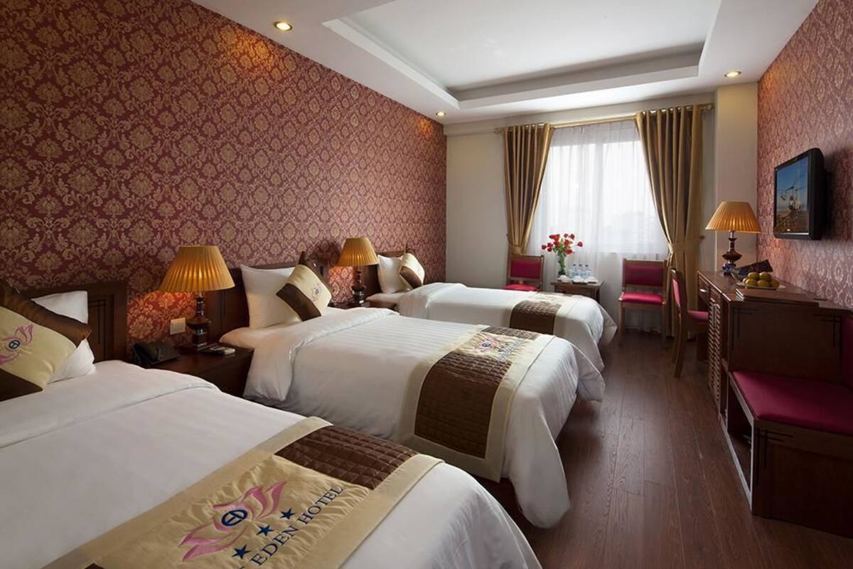 A hotel room with three beds, a desk, and a chair.