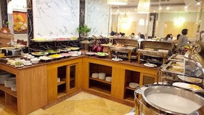 A buffet setup with various food stations, marble walls, and hanging lights. - First Eden Hotel (Hanoi)