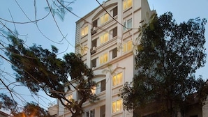 A multi-story hotel with a well-lit entrance, balconies, and a visible staircase leading to the entrance. - First Eden Hotel (Hanoi)