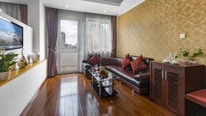 A modern living room with a leather sofa, a glass coffee table, and a television on a wall. - First Eden Hotel (Hanoi)