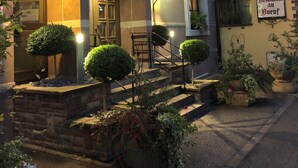 Un hôtel avec une enseigne indiquant « Hôtel du Bois » et une plus petite enseigne signalant la présence d’un restaurant.