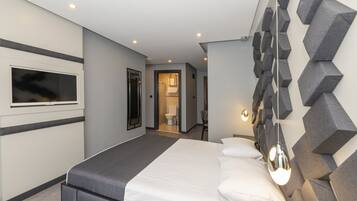 Una habitación de hotel moderna con una cama grande, un televisor de pantalla plana y un diseño de pared geométrico único.