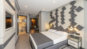 Una habitación de hotel moderna con una cama grande, mesitas de noche, un espejo y una lámpara fijada a la pared.
