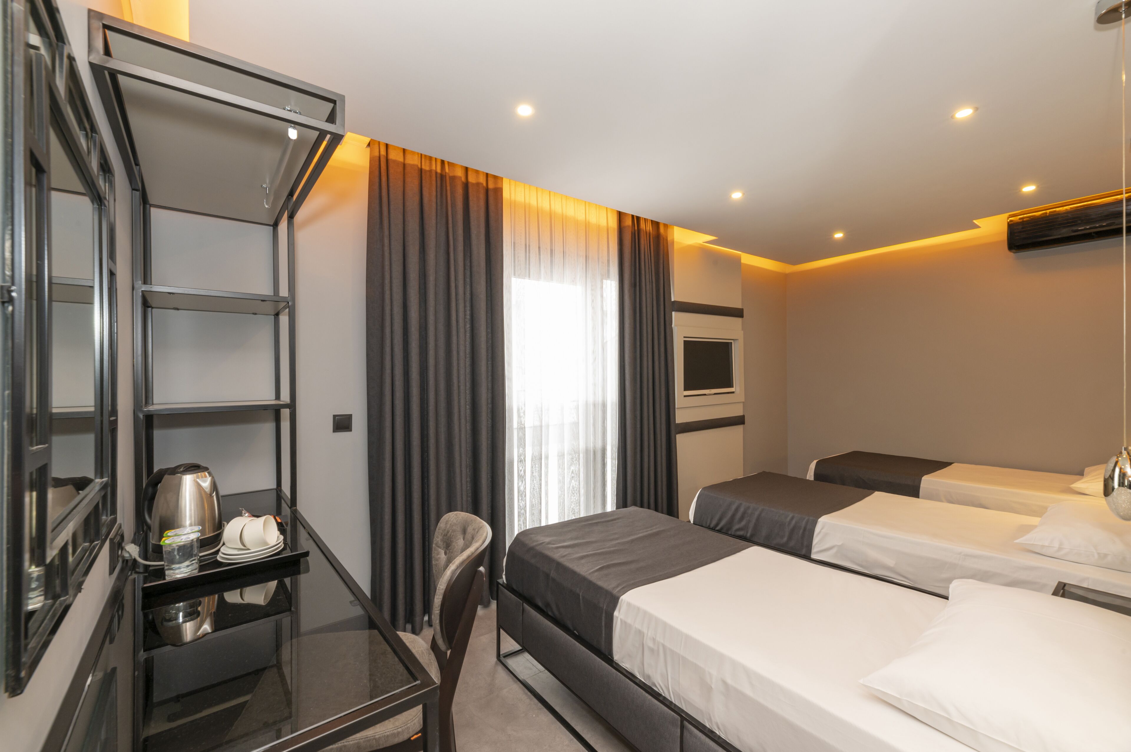 Une chambre d’hôtel équipée d’un bureau, de deux lits, d’une chaise et d’une fenêtre avec des rideaux.