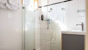 A modern bathroom with a glass-enclosed shower, a white sink, and a towel rack.